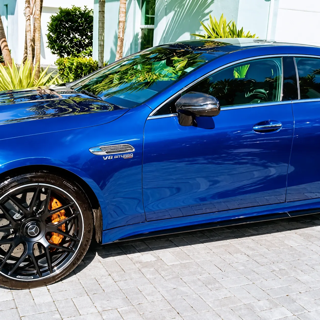 Blue Mercedes-AMG V8 Biturbo parked in luxury driveway with palm trees