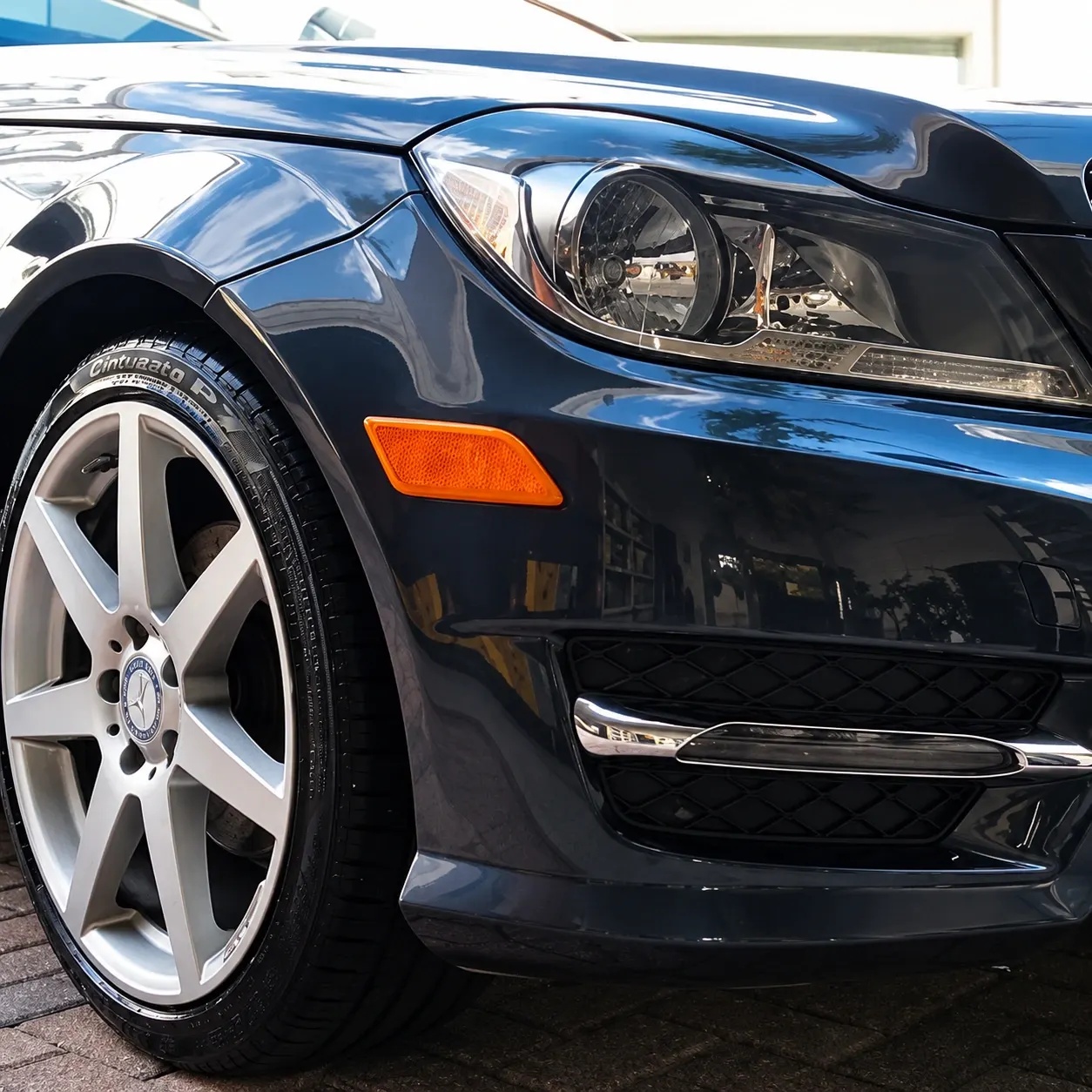 Close-up of sleek black Mercedes-Benz sedan with white alloy wheel and orange side marker light