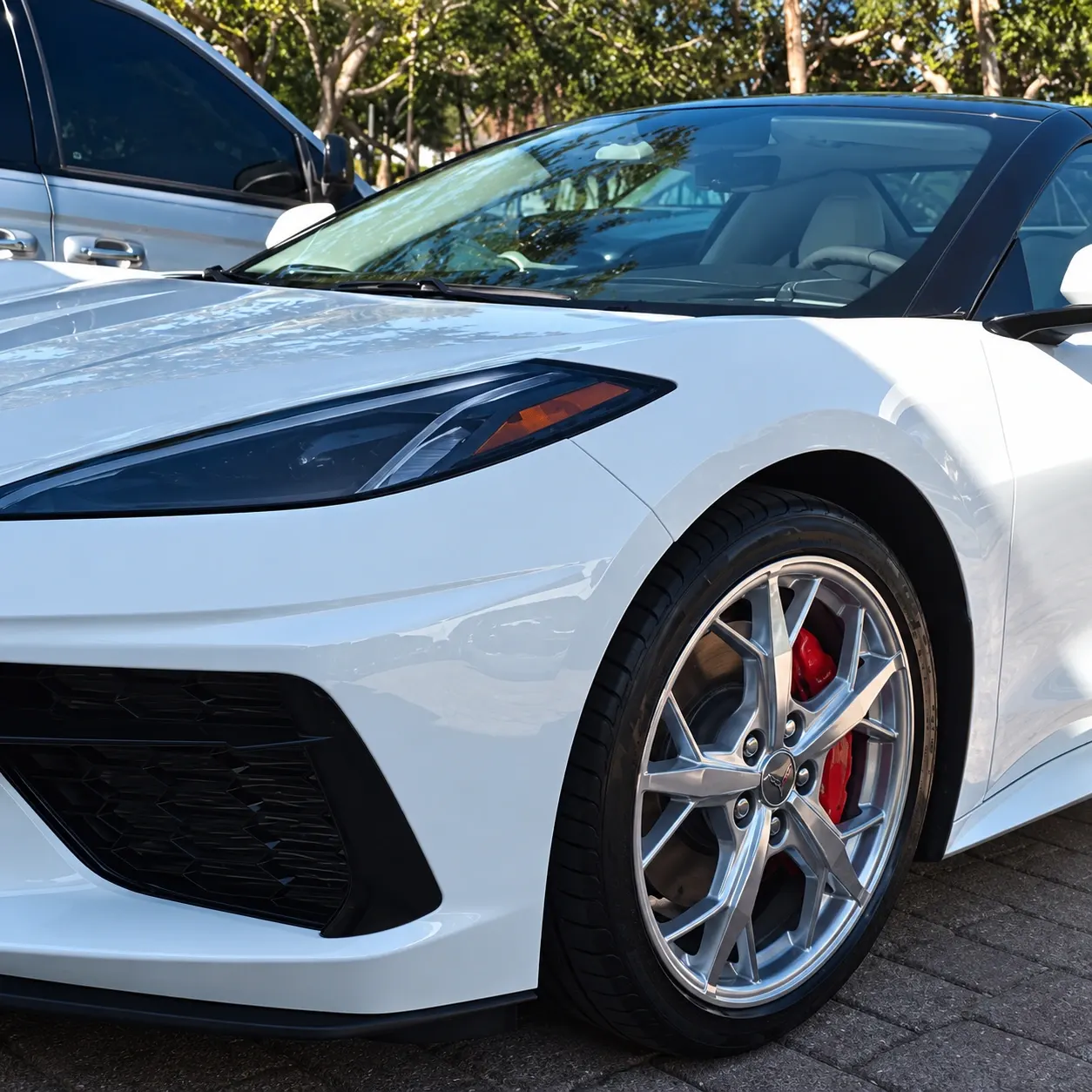 White sports car with silver wheels and red brake calipers parked in lot