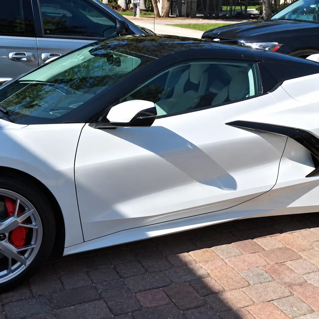 White sports car with open gullwing door parked in driveway