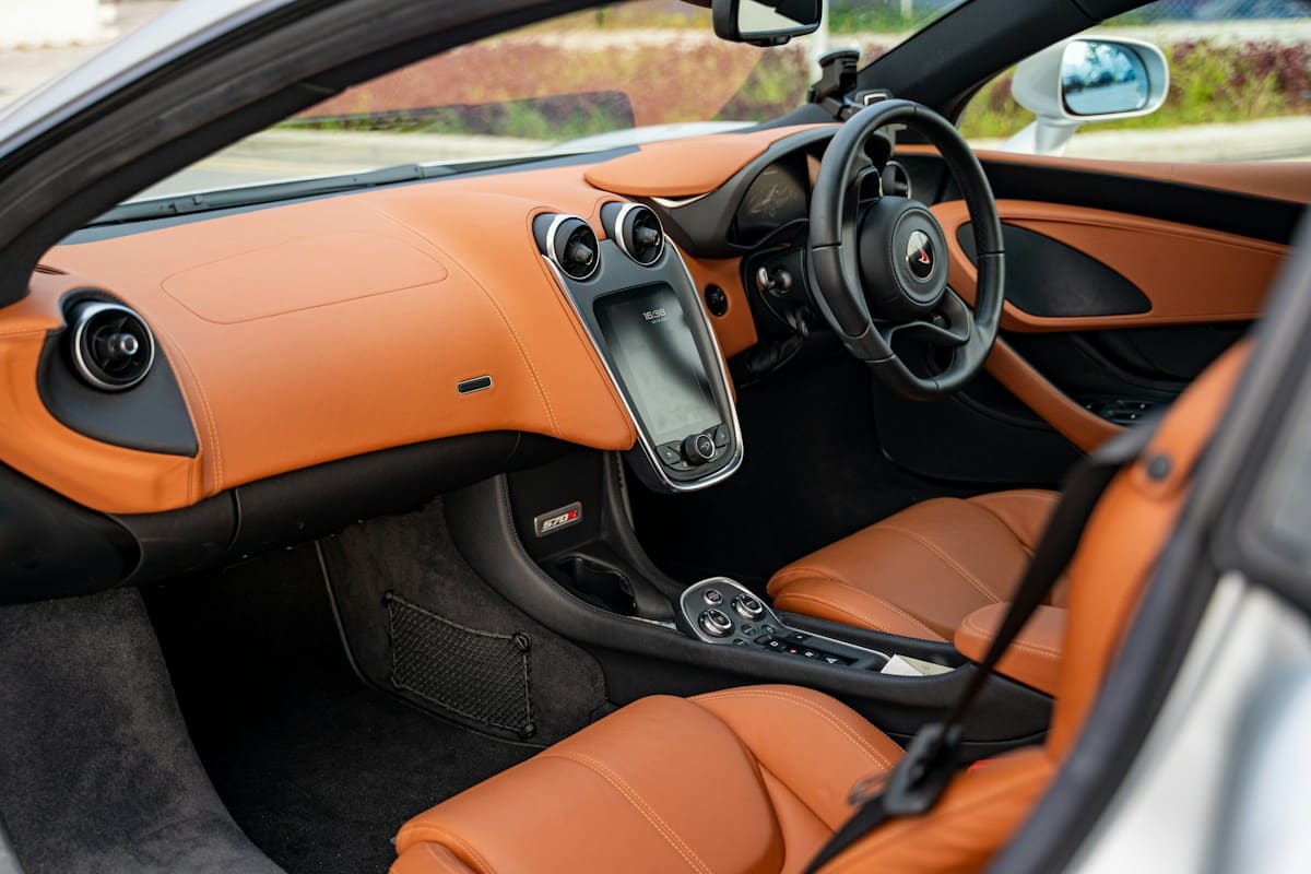 Interior of orange sports car with black and tan leather seats and steering wheel