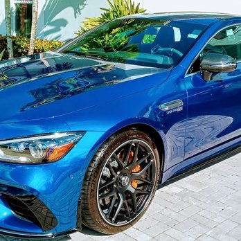 Blue sports car with orange brake calipers parked on brick pavement