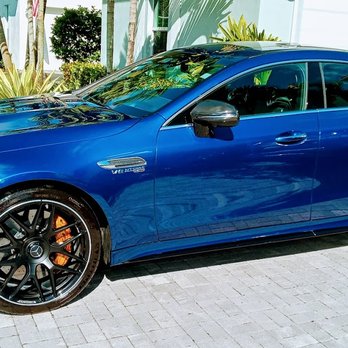 Bright blue sports car parked in driveway with black alloy wheels and orange brake calipers