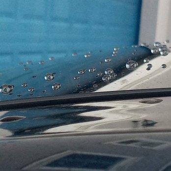 Water droplets on car window with blue sky and vehicles visible in background
