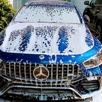 Blue Mercedes-Benz with soap suds during car wash service