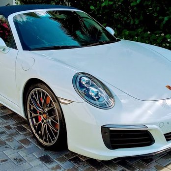 White Porsche 911 with gold wheels parked on brick pavement