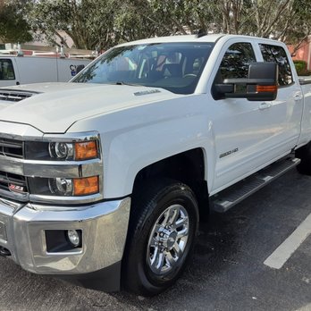 White Chevrolet Silverado pickup truck parked in lot with trees in background