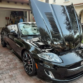 Black convertible sports car with hood open displayed in driveway