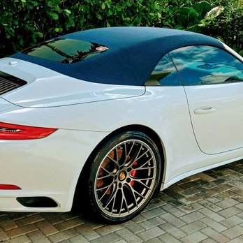 White Porsche 911 coupe with gold wheels parked on brick driveway