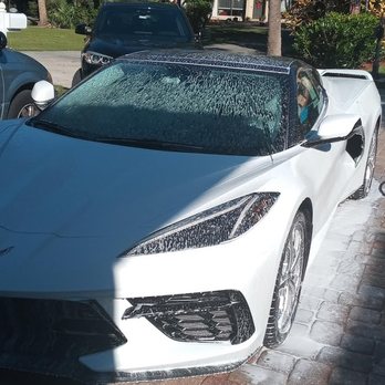 White sports car parked in residential driveway with wet windshield