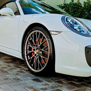 White sports car with orange and red brake calipers parked on brick pavement