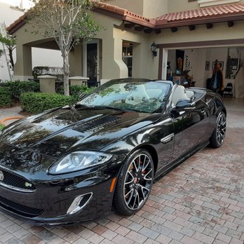 Black convertible sports car parked in residential driveway with garage